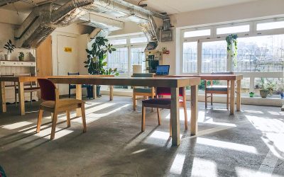 Wooden tables and chairs in a sun filled co-working space at The Remakery, Brixton.