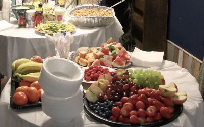 Tables covered in fruit, paper plates and hot food at The Remakery.
